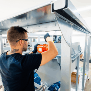 Engineer wearing safety goggles working on an automated testing machine with tools