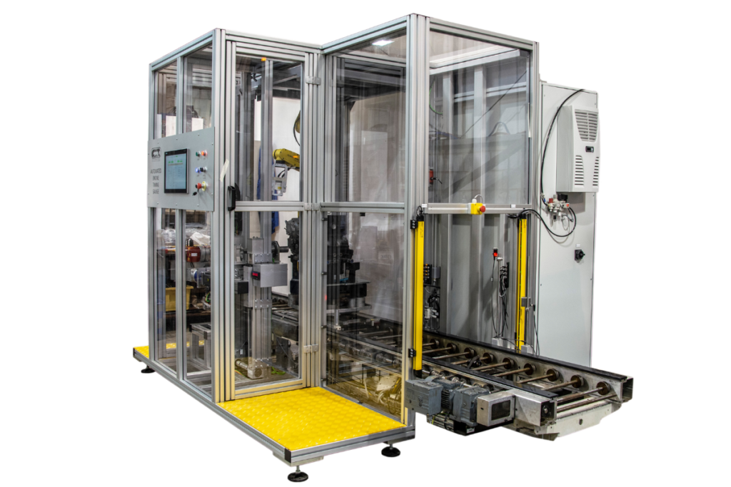 Automated system integration cell with robotic handling, PLC control, safety guarding, and conveyor-based material flow.
