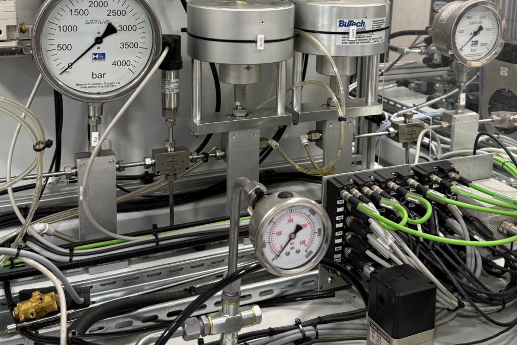 Subcontract testing facility with calibrated pressure gauges, hydraulic and pneumatic test rig, and instrumentation for performance validation.
